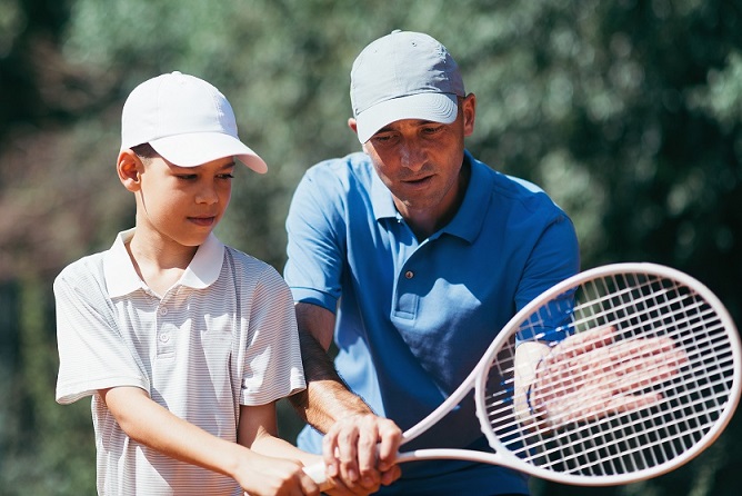 Tennis Coach Teaching Boy how to Play Tennis. Tennis Lesson 