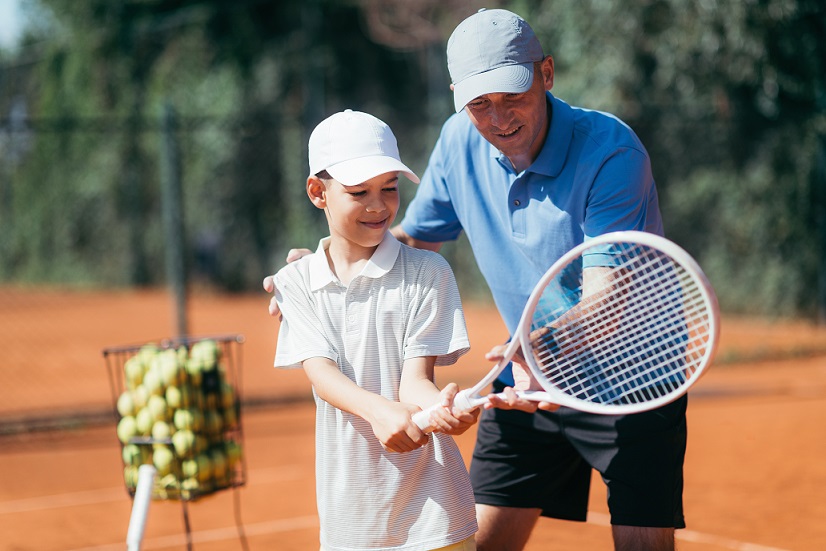 Tennis Coach Teaching Boy how to Play Tennis. 